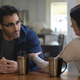 Clark Kent and Lois Land sit at their kitchen table and talk over coffee.